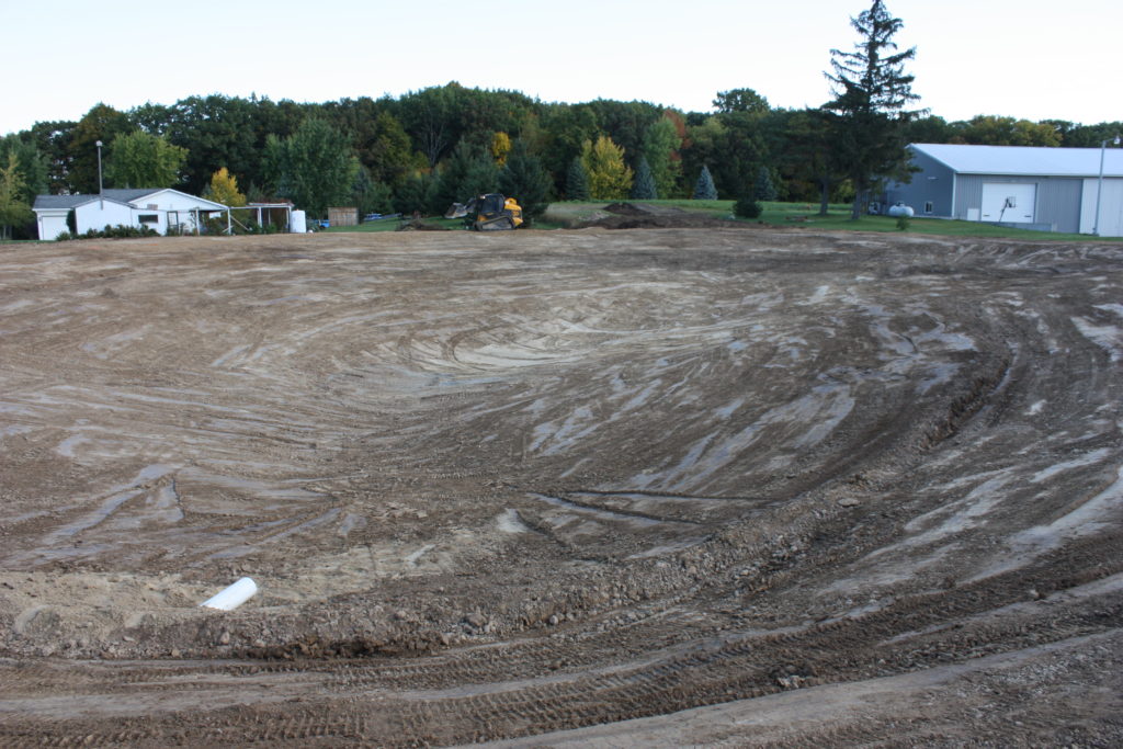 Backyard swim pond excavation with overflow water line far away view