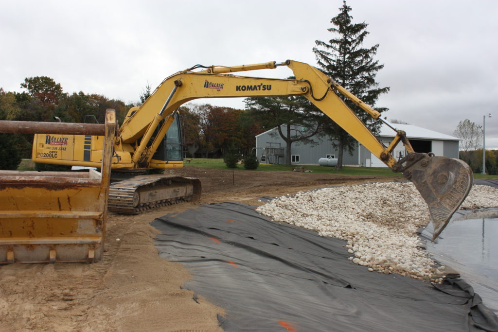 Backyard swim pond stone blanket placement on shoreline