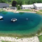 Aerial view of ultimate backyard transformation pond with fountain, pier/dock, and inflatables